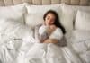 Quelle couette choisir selon la saison ? femme qui sert sa couette agréable